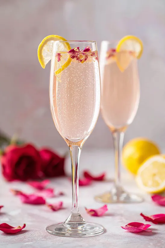 Zwei Gläser rosa Limonade mit Zitronenscheiben und Rosenblättern.