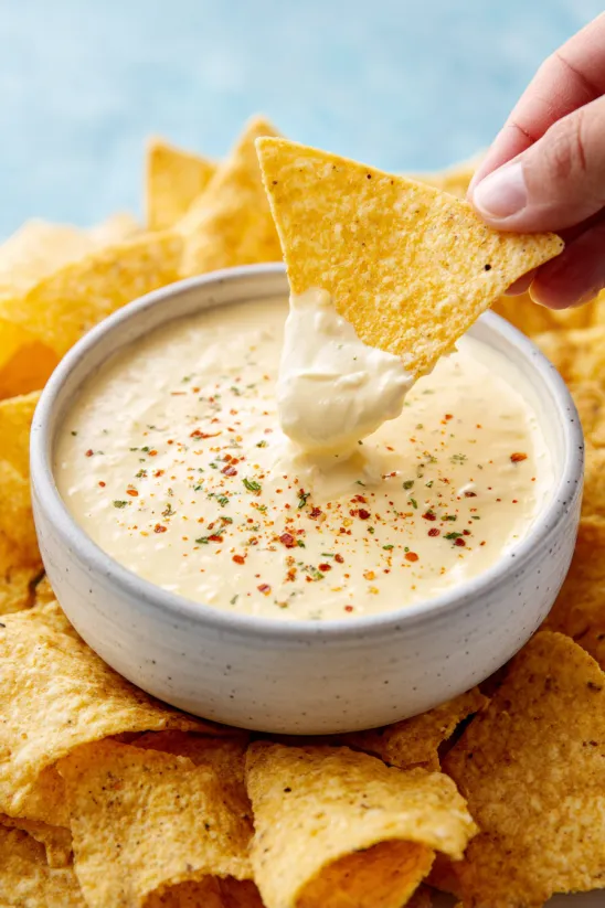 Ein Handrisselchen aus einer Schüssel mit einer cremigen mexikanischen Sauce, die als Salsa Blanca bekannt ist.