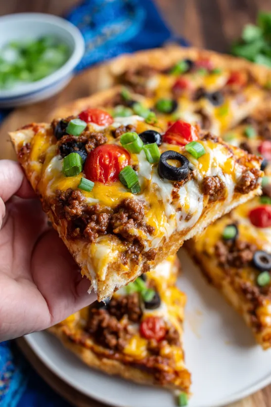 Ein Stück mexikanische Pizza mit Tomaten, Oliven und Käse.