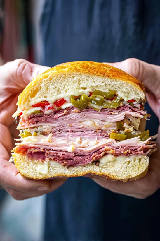 Jemand hält ein Muffaletta Sandwich.