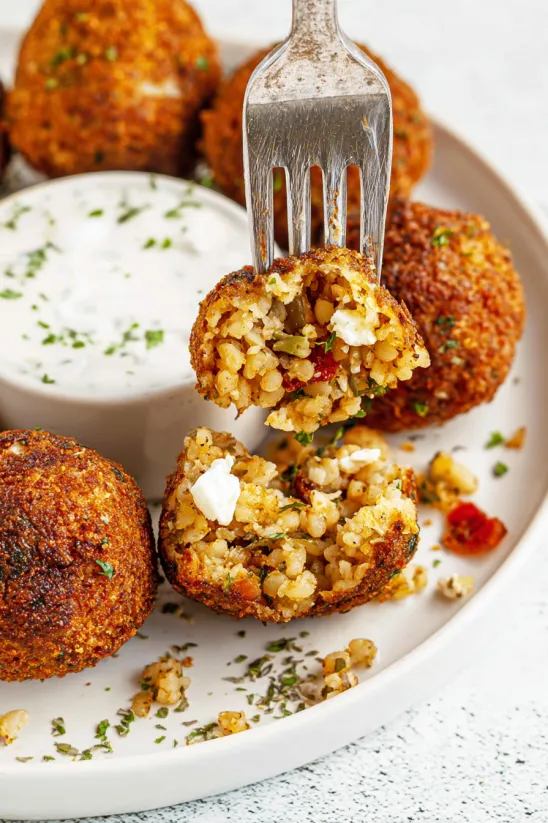 Ein Teller mit Boudin-Bällchen und Gabel in der Mitte.