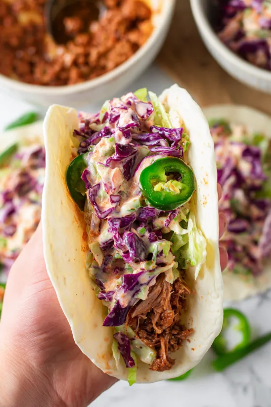 Eine Hand hält einen Corned-Beef-Taco mit cremigem Krautsalat.