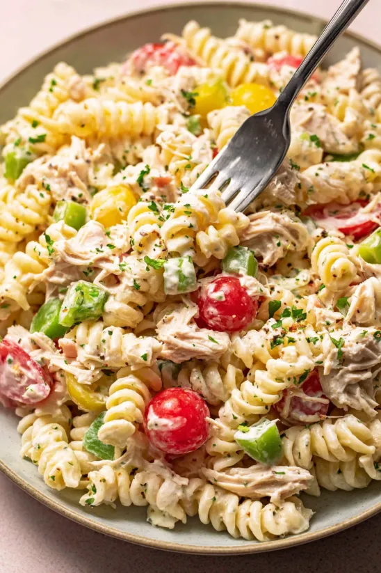Eine Gabel steckt in einer Schüssel Thunfisch-Nudelsalat.