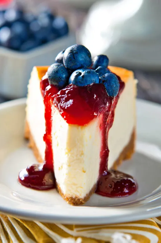 Ein Stück Käsekuchen mit Blaubeeren on top.