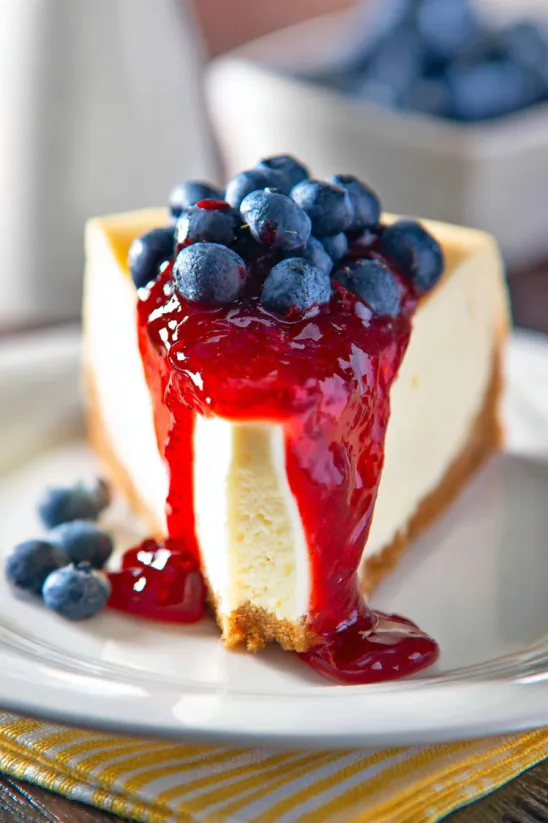 Ein Stück Käsekuchen, getoppt mit Heidelbeeren.