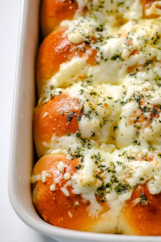 Weiße Schale mit käsigen, knoblauchigen Hawaiian Rolls.