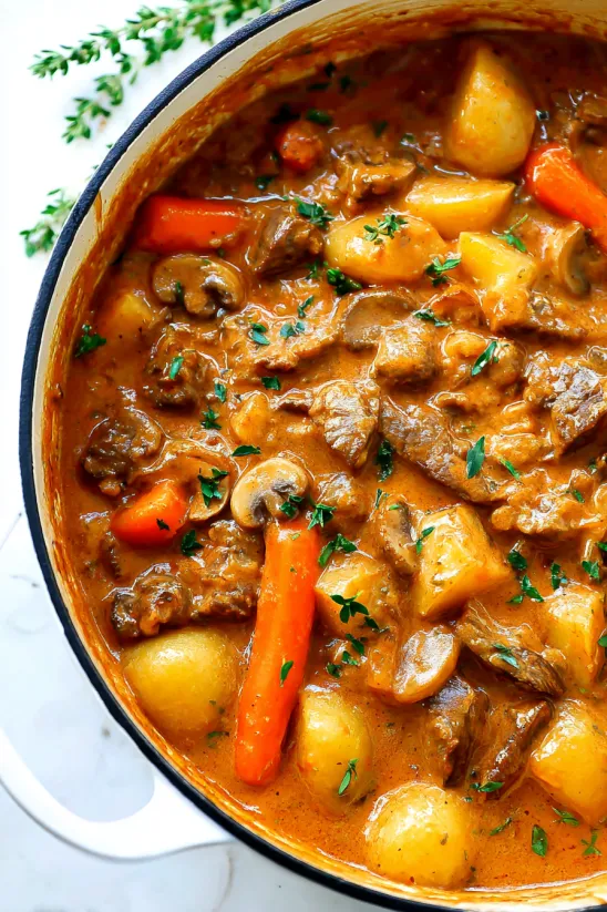 Eine Schüssel mit Schmortopf voller Fleisch, Kartoffeln, Möhren und Pilzen.