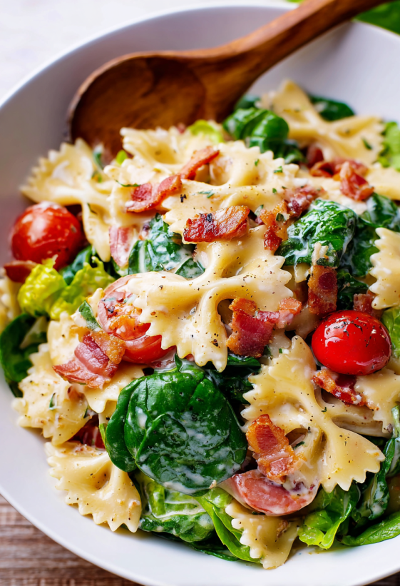 Große Schüssel voll Nudelsalat mit knusprigem Speck und Tomaten.