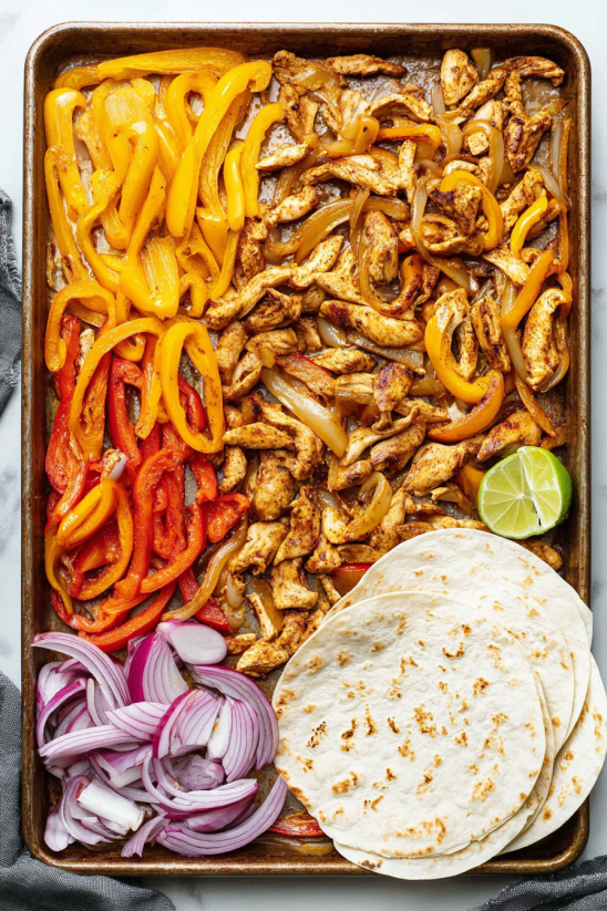 Eine Tafel mit verschiedenen Zutaten für Fajitas, darunter Chicken, Onions, Peppers, Lime und Limetten.