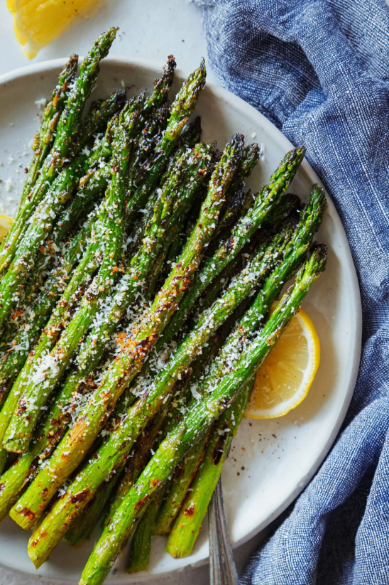 Ein weißer Teller mit Asparagus, der mit Salz und Pfeffer zubereitet wurde.