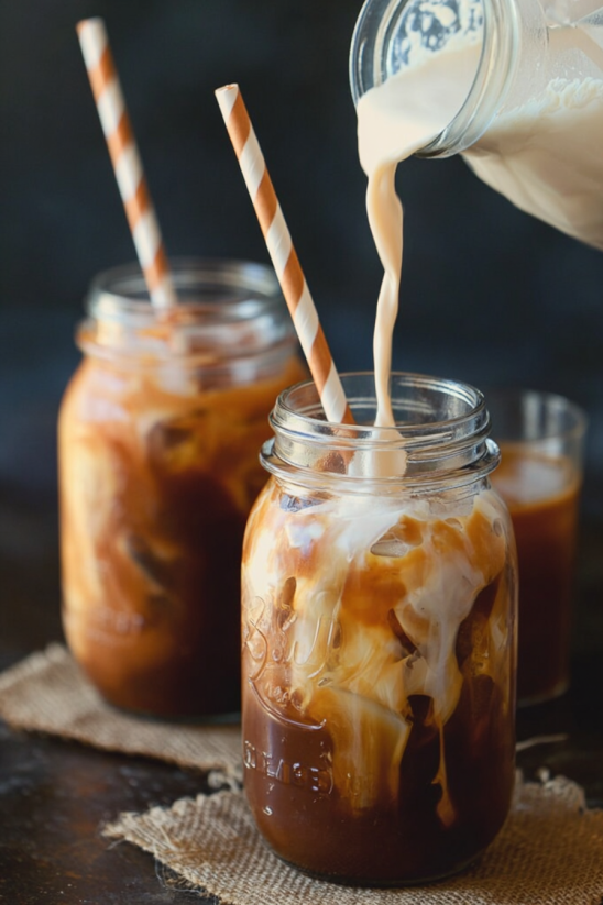 Zwei Glas mit Thai Iced Tea, die mit Stroh umwickelt sind.