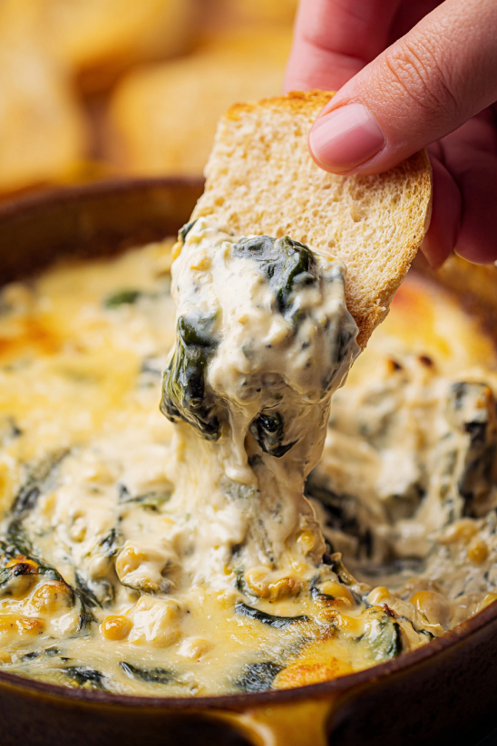 Eine Person hält eine Schüssel mit Rajas (Creamy Roasted Poblanos) in der Hand und schöpft eine Portion in ein Brot.