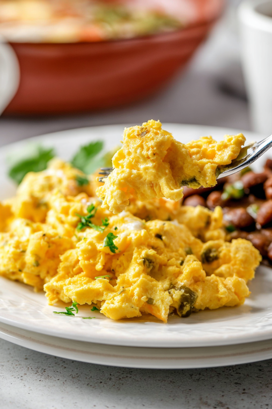 Ein wei&szlig;er Teller mit Huevos a la Mexicana (Scrambled Mexican Eggs) auf einem Tisch.