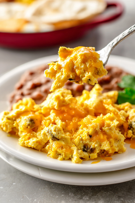 Ein weißer Teller mit Huevos a la Mexicana (Scrambled Mexican Eggs) auf einem Tisch.