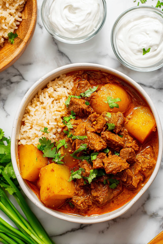 Ein Becher mit mexikanischer Carne Guisada, die mit Rice und verschiedenen Gemüse garniert ist.