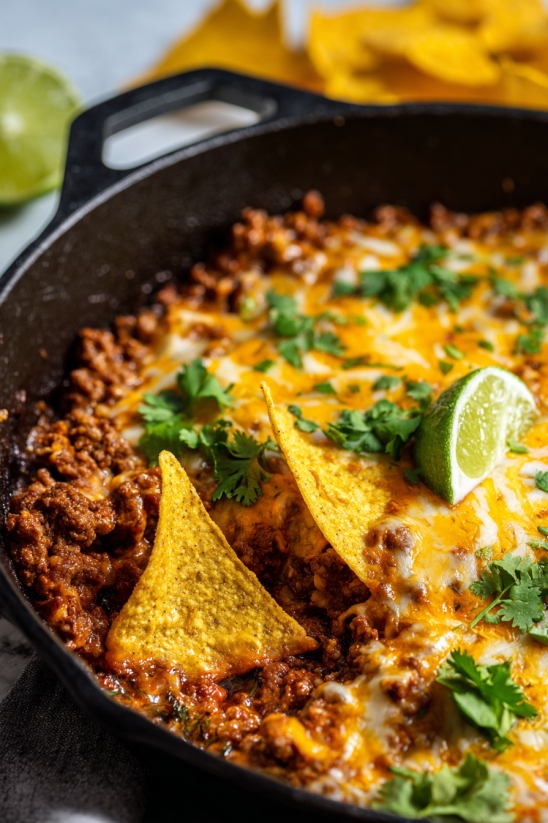 Eine Schüssel mit Queso Fundido, garniert mit grünen Zwiebeln und Limetten.