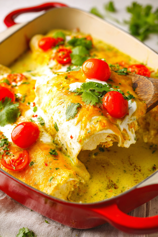 Ein Bild von einer Schüssel mit Breakfast Enchiladas, die mit Tomaten, Koriander und anderen Zutaten garniert sind.