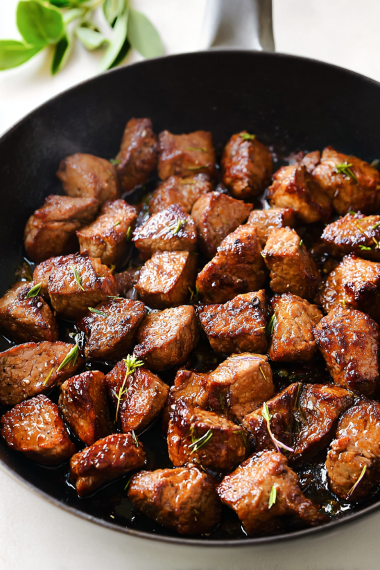 Ein Topf mit Steak Bites, die in Garlic Butter getaucht sind.