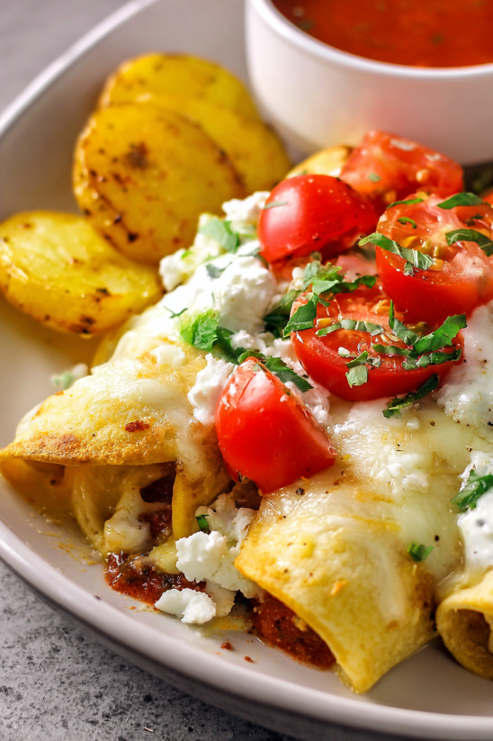 Ein Bild von einer Platte mit Easy Chicken Taquitos, die mit Tomaten, Käse und Zwiebeln garniert sind.