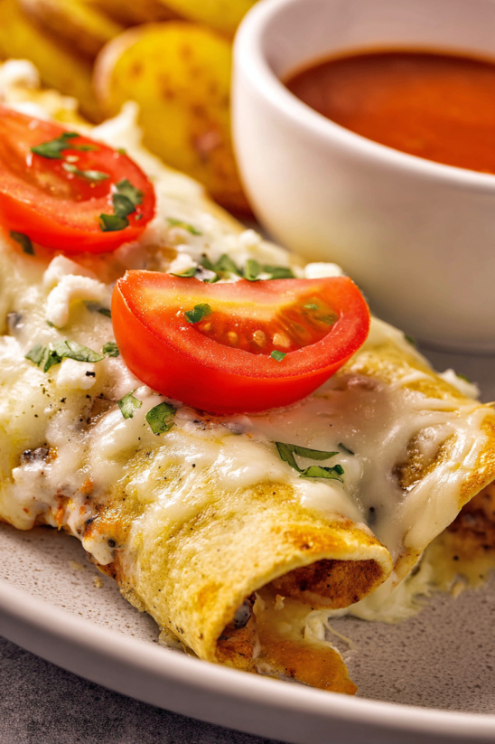 Ein Stück Easy Chicken Taquitos mit Tomaten und Käse auf einem Teller.