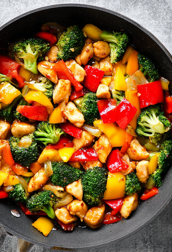 Ein Bild von einer Chicken Stir Fry mit vielen verschiedenen Zutaten wie Broccoli, Paprika, Zwiebeln und mehr.