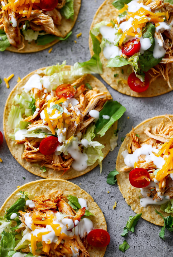 Ein Bild von Slow Cooker Chicken Ranch Tacos, die auf einem Tisch liegen.