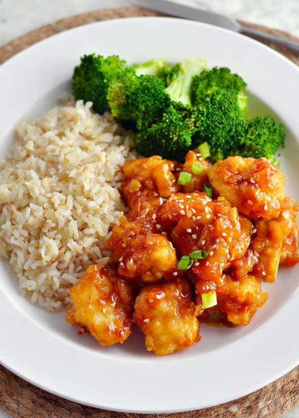 Ein weißer Teller mit Baked Sweet and Sour Chicken und Fried Rice.