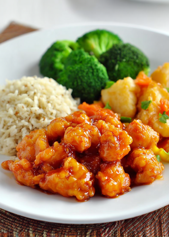 Ein weißer Teller mit einer Mischung aus Reis, Kartoffeln, Broccoli und Chicken.