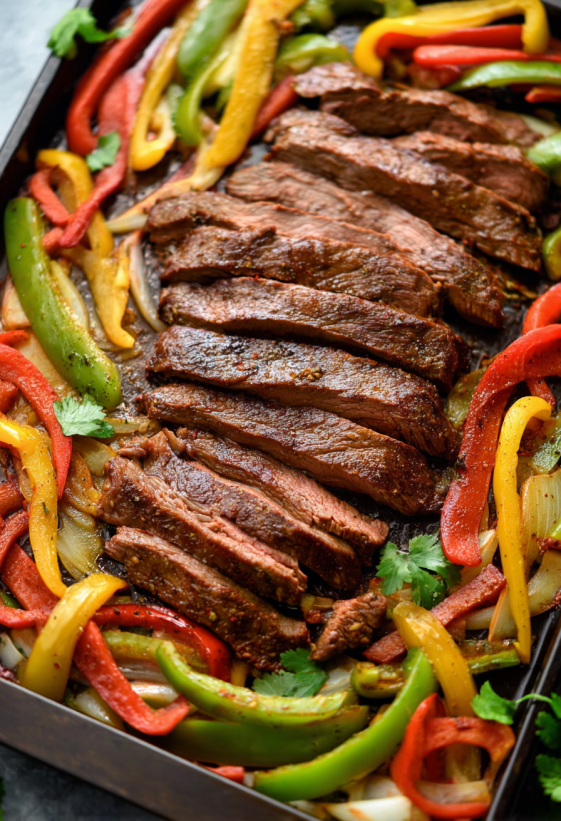 Eine Schüssel mit Steak, Paprika, Zwiebeln und anderen Zutaten, die für eine Fajita zutreffend sind.