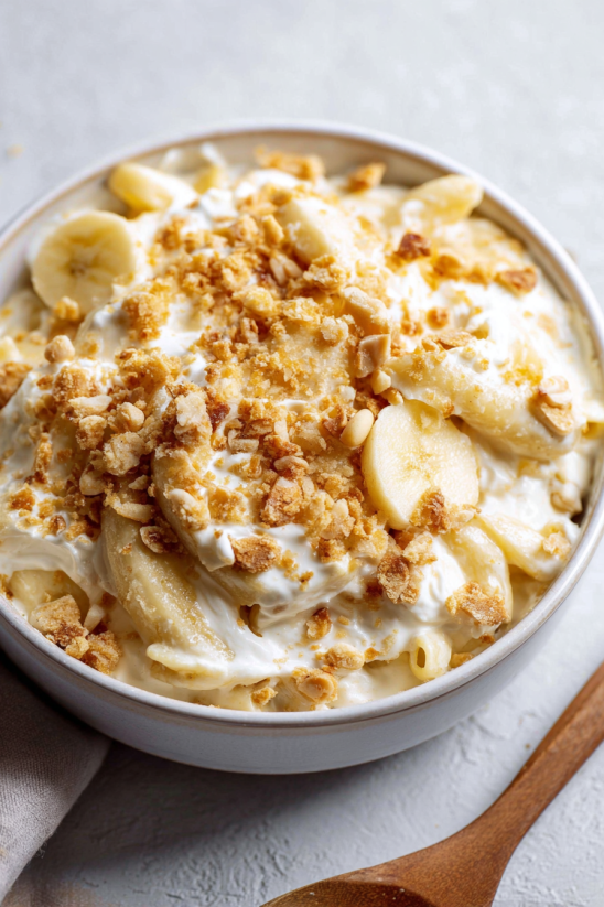 Ein Glas mit Bananenpudding, der mit Bananen, Nüssen und Schlag crem aufgetragen ist.