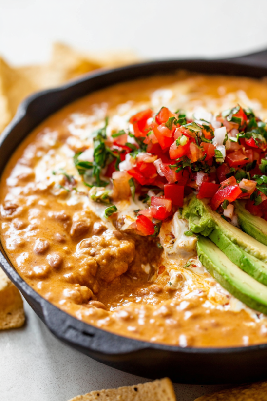 Ein Taco Beer Cheese Dip mit Avocado und Tomaten.