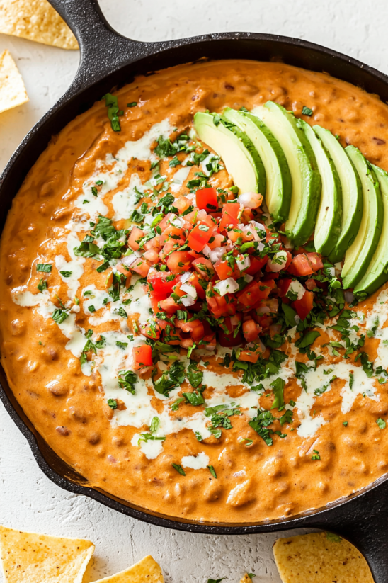 Ein Taco Beer Cheese Dip mit Avocado und Tomaten.