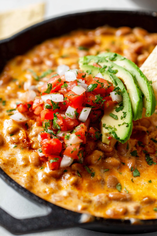 Ein Taco Beer Cheese Dip mit Avocado und Tomaten.