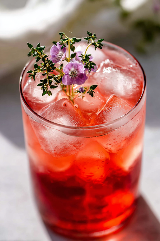 Ein Glas mit einer Transfusion-Getr&auml;nk, das mit Eis und Blumen garniert ist.