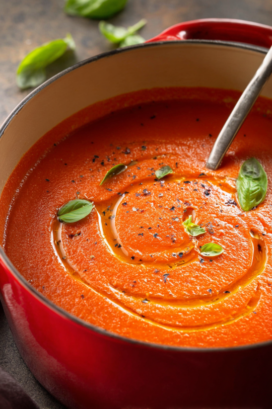 Ein rotes, cremiges Tomatensoep in einem roten Topf.
