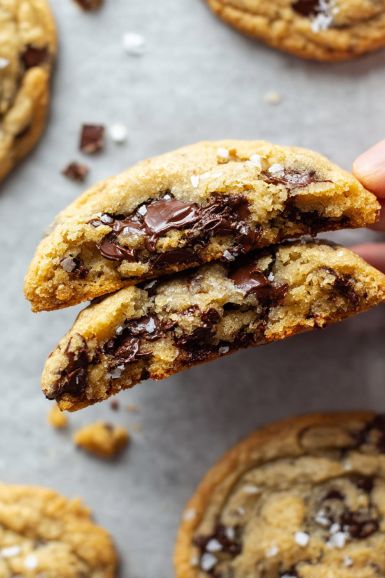 Ein Stück Chocolate Chunk Cookies wird von einer Hand gehalten.