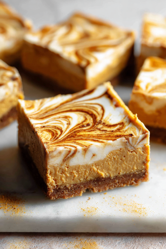 Eine Schicht Pumpkin Swirl Cheesecake Bars auf einem Teller.