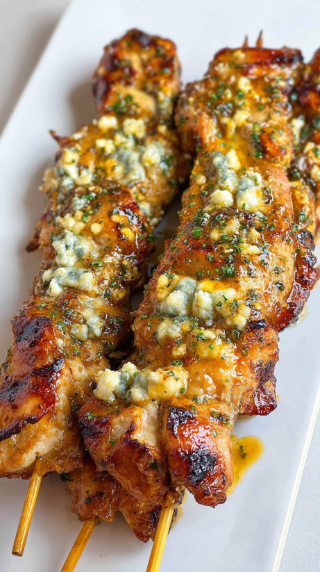 Zwei Stangen Ranch Garlic Parmesan Chicken Skewers auf einem weißen Teller.