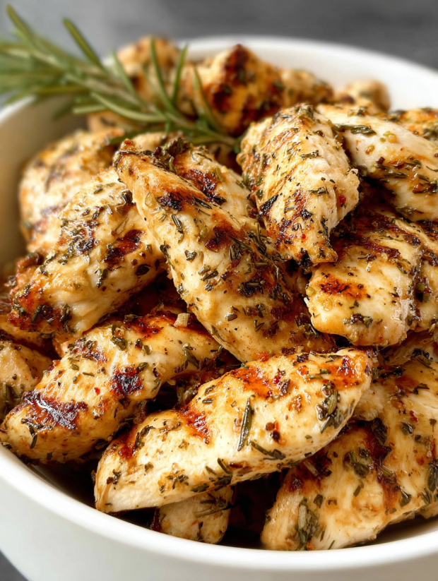 Ein weißer Teller mit grilled chicken nuggets, die mit Parsley garniert sind.