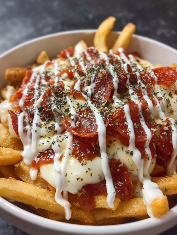 Eine Schüssel mit Pepperoni Pizza Fries, die mit Mayonnaise und Kräutern garniert sind.