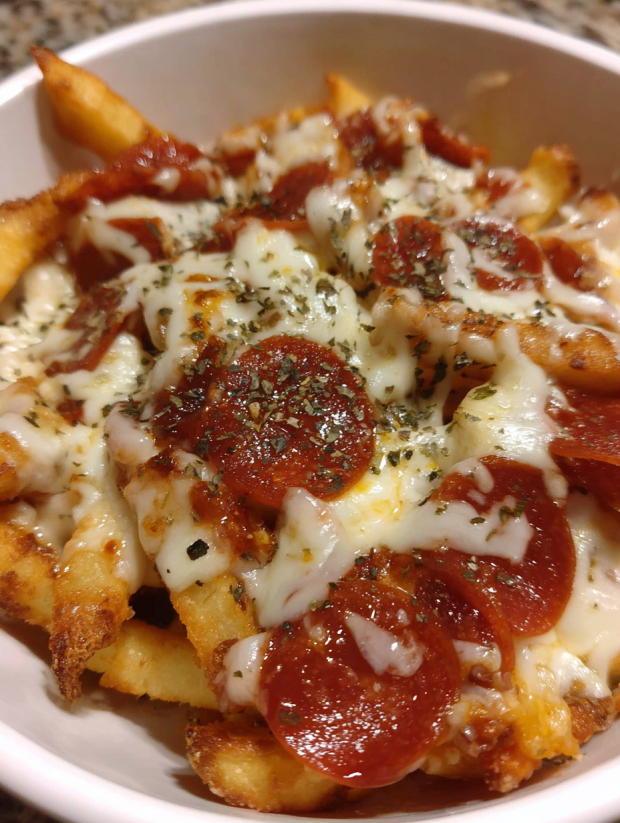Eine Schüssel mit Pepperoni Pizza Fries, die mit Käse und Paprika garniert sind.