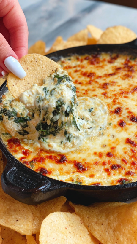 Eine Person hält eine Tortilla in der Hand und schneidet sie in kleine Stücke. Diese Stücke werden in eine Queso Spinach Dip gegeben.
