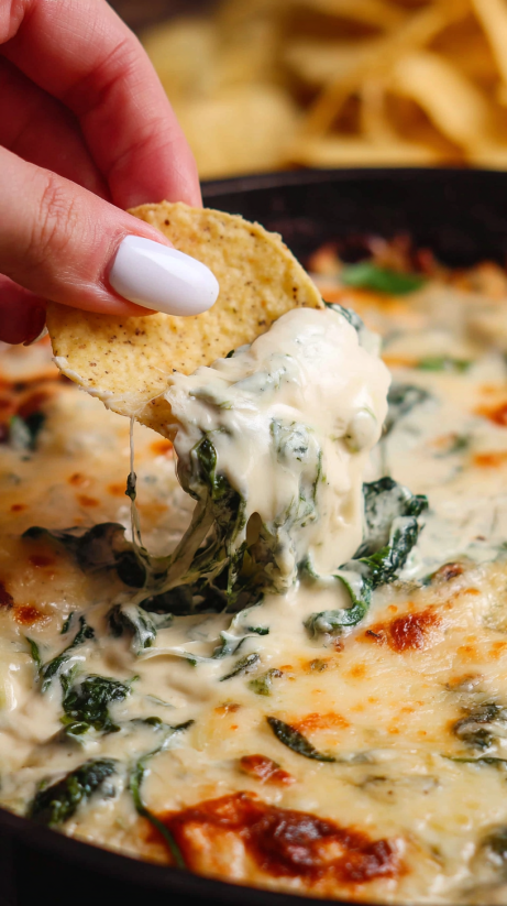 Eine Hand greift nach einer Queso Spinach Dip.