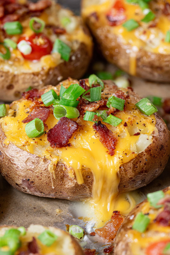 Ein Loaded Baked Potato Slices mit Bacon, Tomaten, Zwiebeln und Käse.