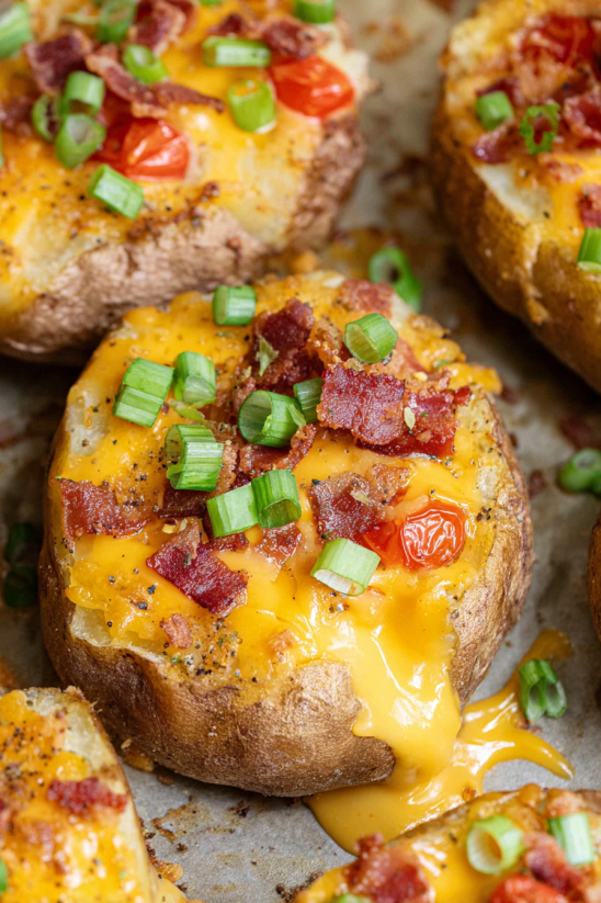 Ein Loaded Baked Potato Slices mit Bacon, Tomaten und Zwiebeln.
