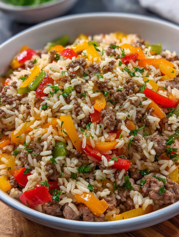 Ein großer Topf mit einer Mischung aus Reis, Kartoffeln, Zwiebeln, Paprika, Tomaten und Rindfleisch.