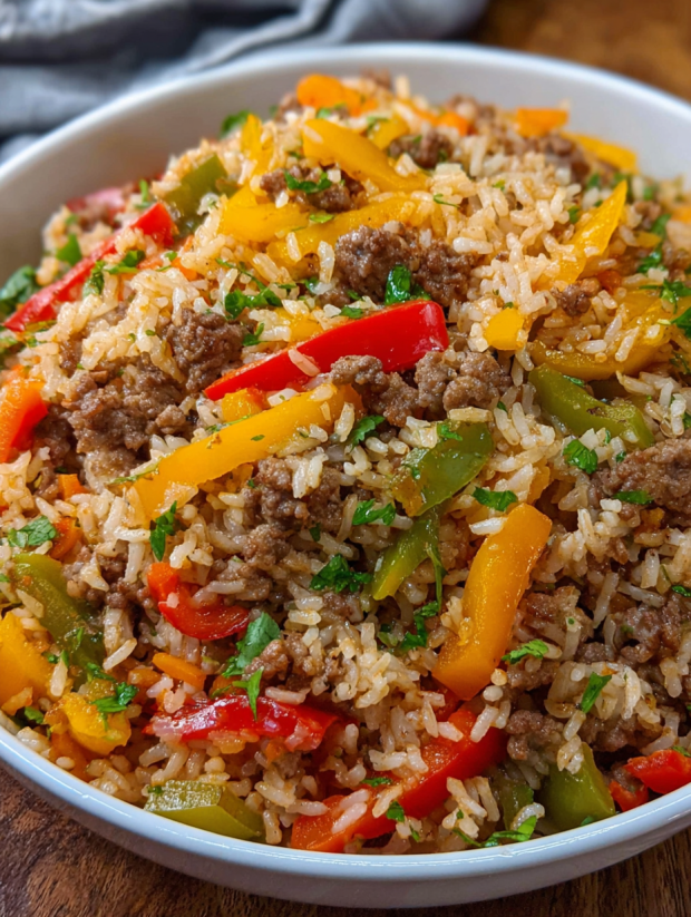 Ein großer Topf mit einer Mischung aus Reis, Rindfleisch, Paprika, Zwiebeln und Tomaten.