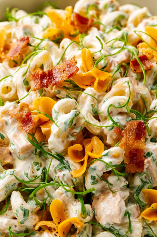 Bacon Ranch Pasta Salad mit grünen Blättern und Pasta.