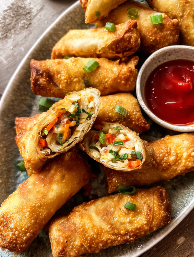 Ein Plate mit Chicken Egg Rolls, die in einem Glas mit Sweet & Sour Sauce serviert werden.
