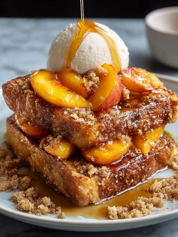 Ein Bild von einer Peach Cobbler French Toast, die mit Eis und Zucker serviert wird.